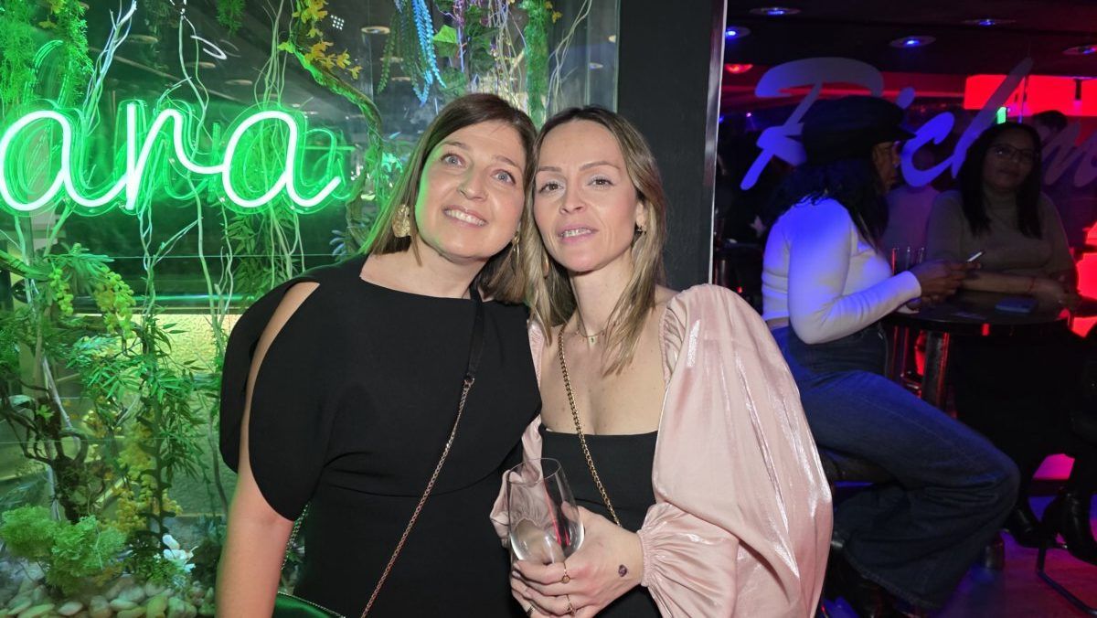 Dos mujeres sonriendo en un evento en Richmond con luces de neón