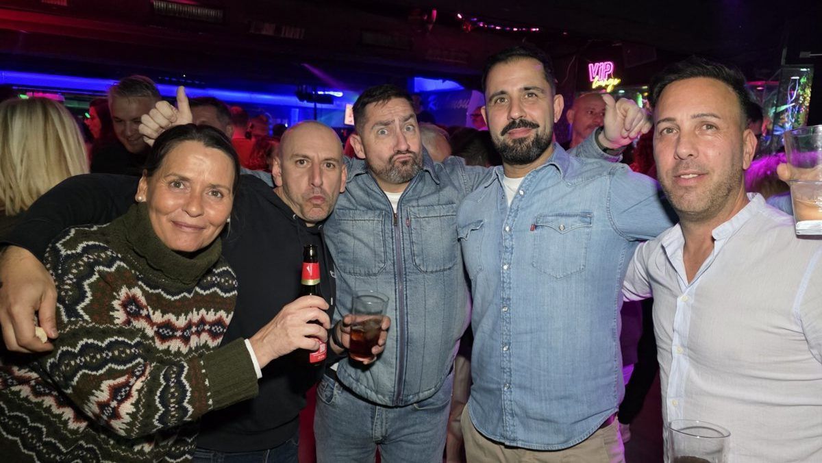Grupo de amigos disfrutando en una fiesta con bebidas en la mano.