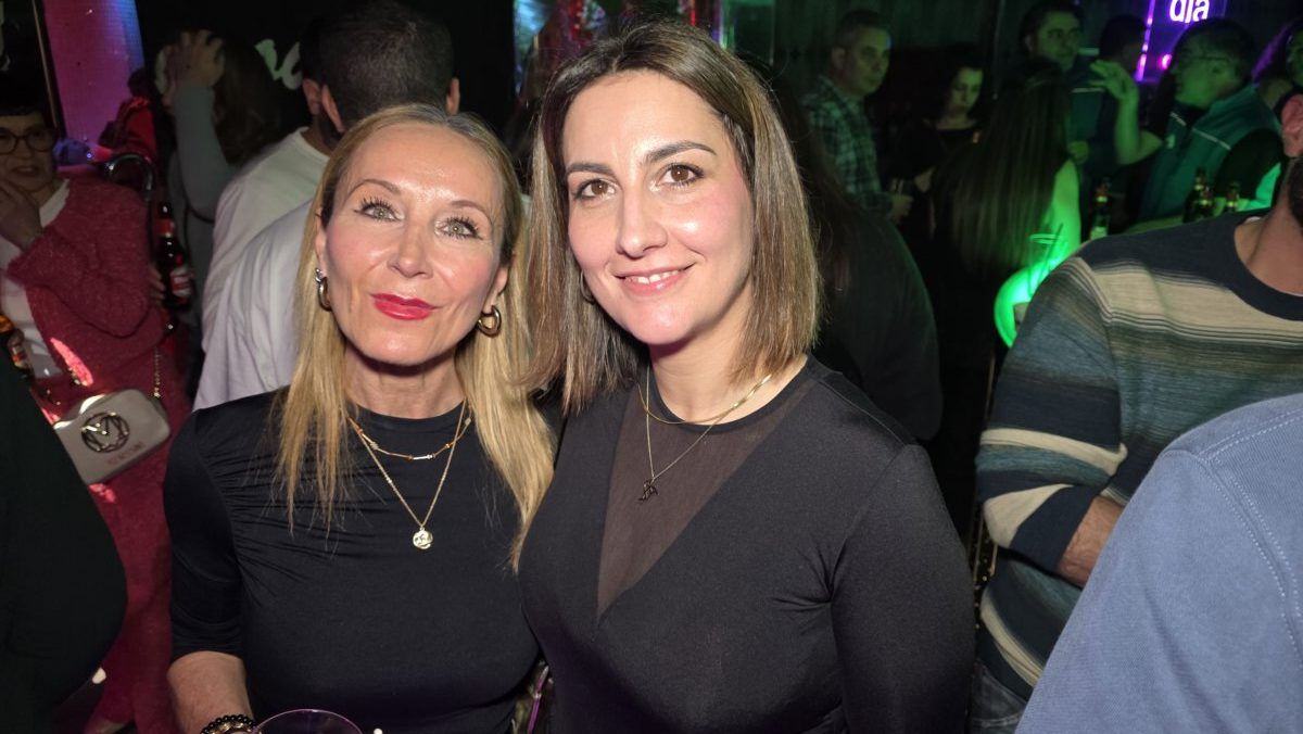 Dos mujeres sonriendo en una fiesta con luces de colores