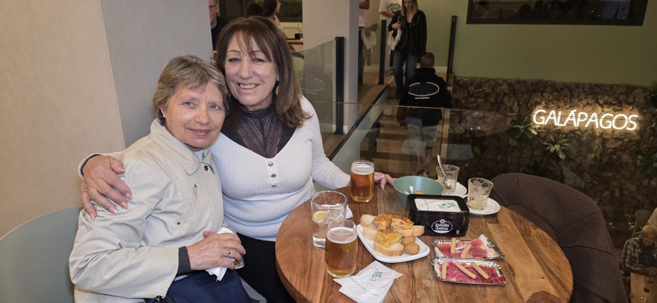 Dos mujeres sonrientes en el Bar Galápagos con bebidas y comida.