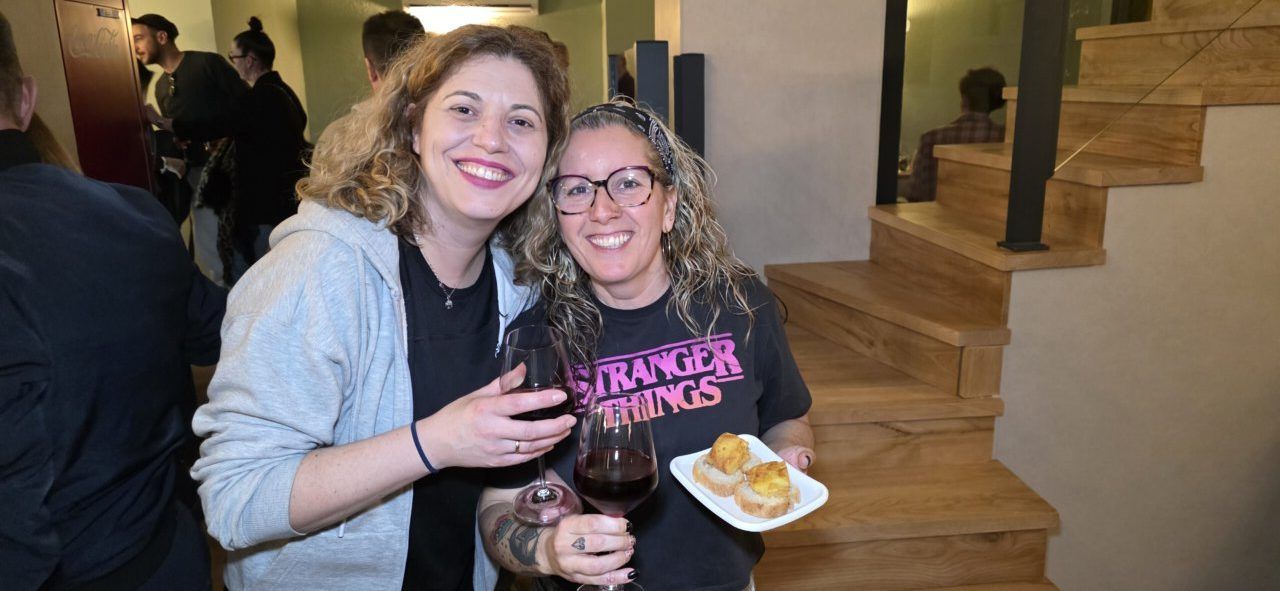 Dos mujeres sonriendo con copas de vino en la inauguración del bar Galápagos.