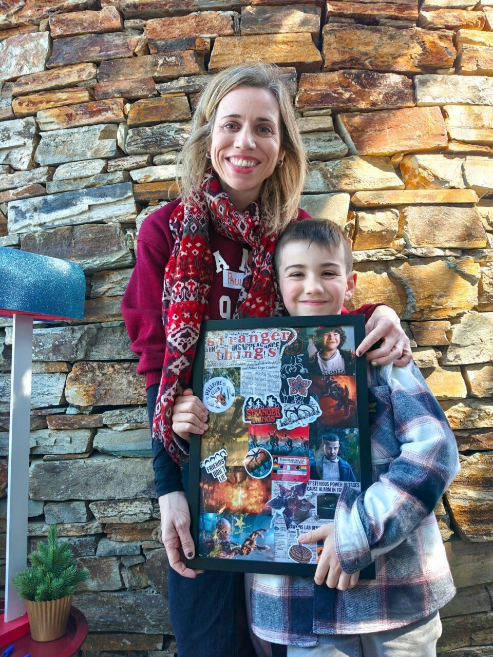Mujer y niño sosteniendo un marco decorado con stickers de Stranger Things
