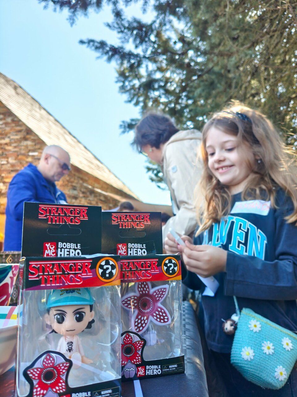Niña sonriente con figuras de Stranger Things en un taller