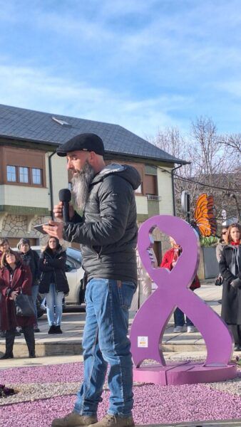 Hombre hablando en un evento del 8M junto a una escultura en Fabero