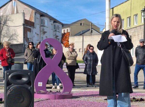 Mujer leyendo en un evento del 8M en Fabero junto a una escultura