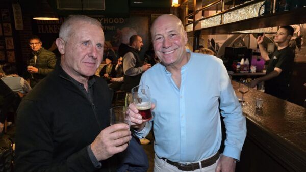 Dos hombres sonrientes sosteniendo bebidas en La Galería de Ponferrada