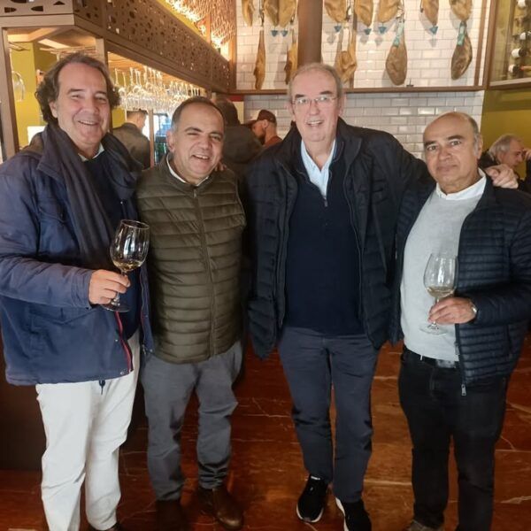 Cuatro hombres disfrutando de una reunión en un restaurante con vino