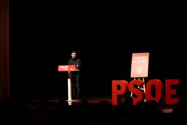 Un orador en un evento del PSOE en Fabero con carteles rojos
