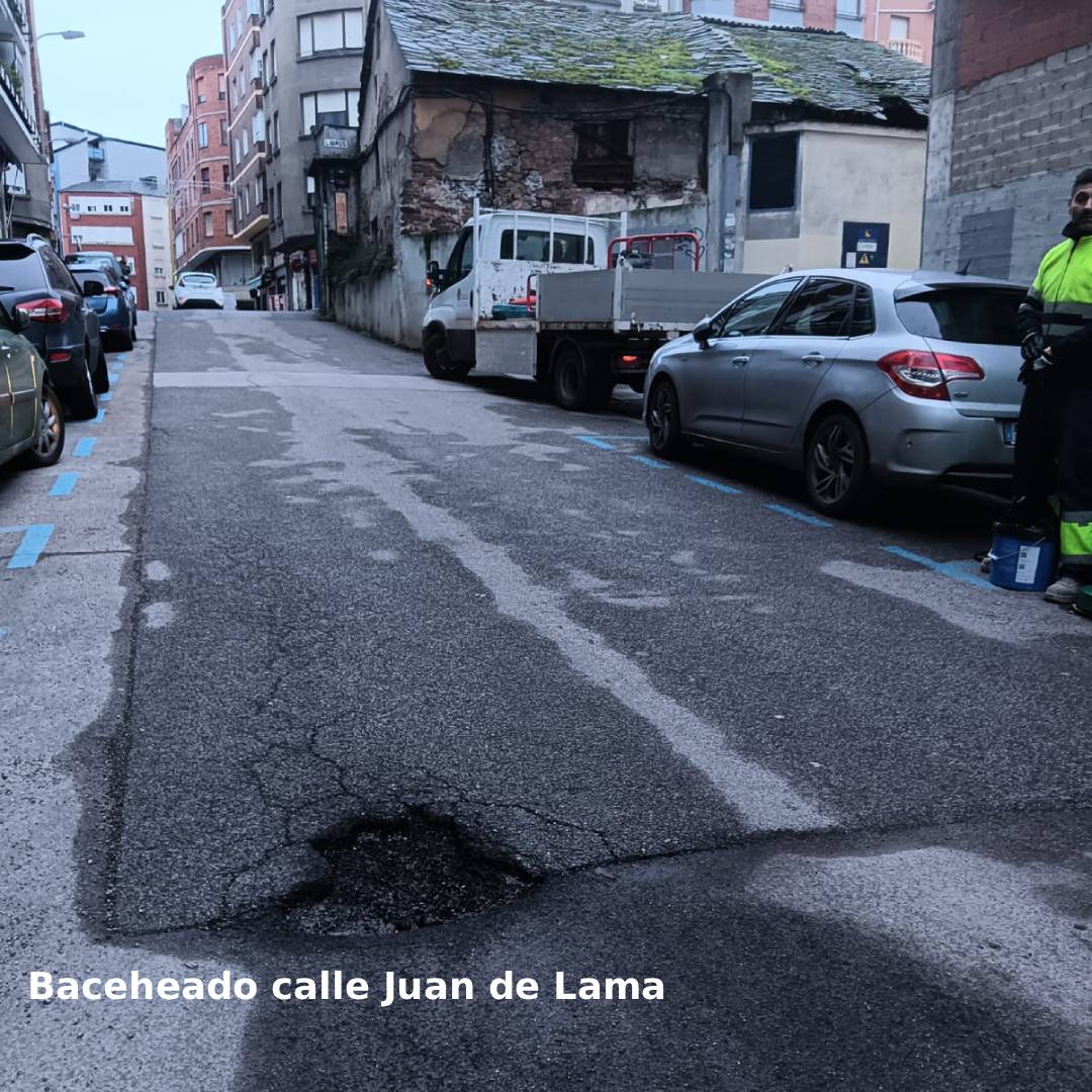 Calle Juan de Lama con bache reparado y vehículos estacionados.