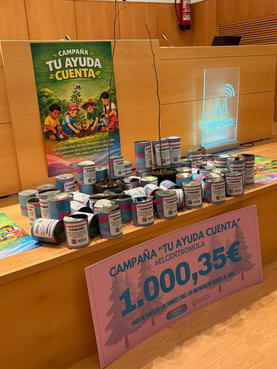 Mesa con huchas y cartel de campaña para plantar robles en Ponferrada
