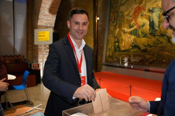 Persona votando en un evento electoral con fondo decorativo