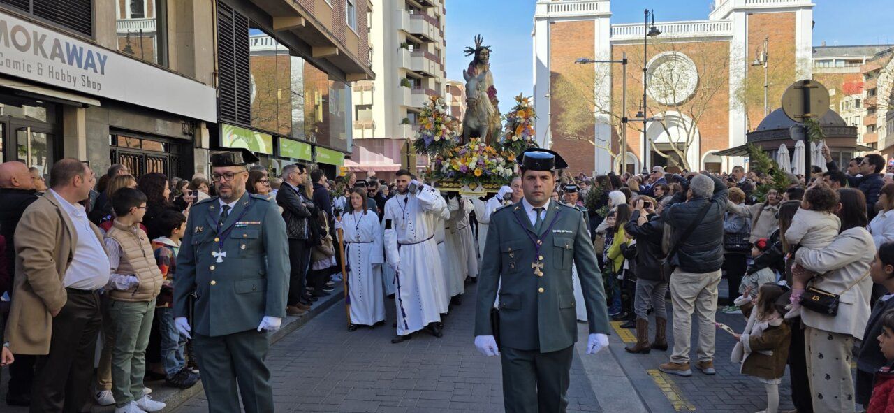 Celebración del Domingo de Ramos en Ponferrada con una multitud y un paso religioso.