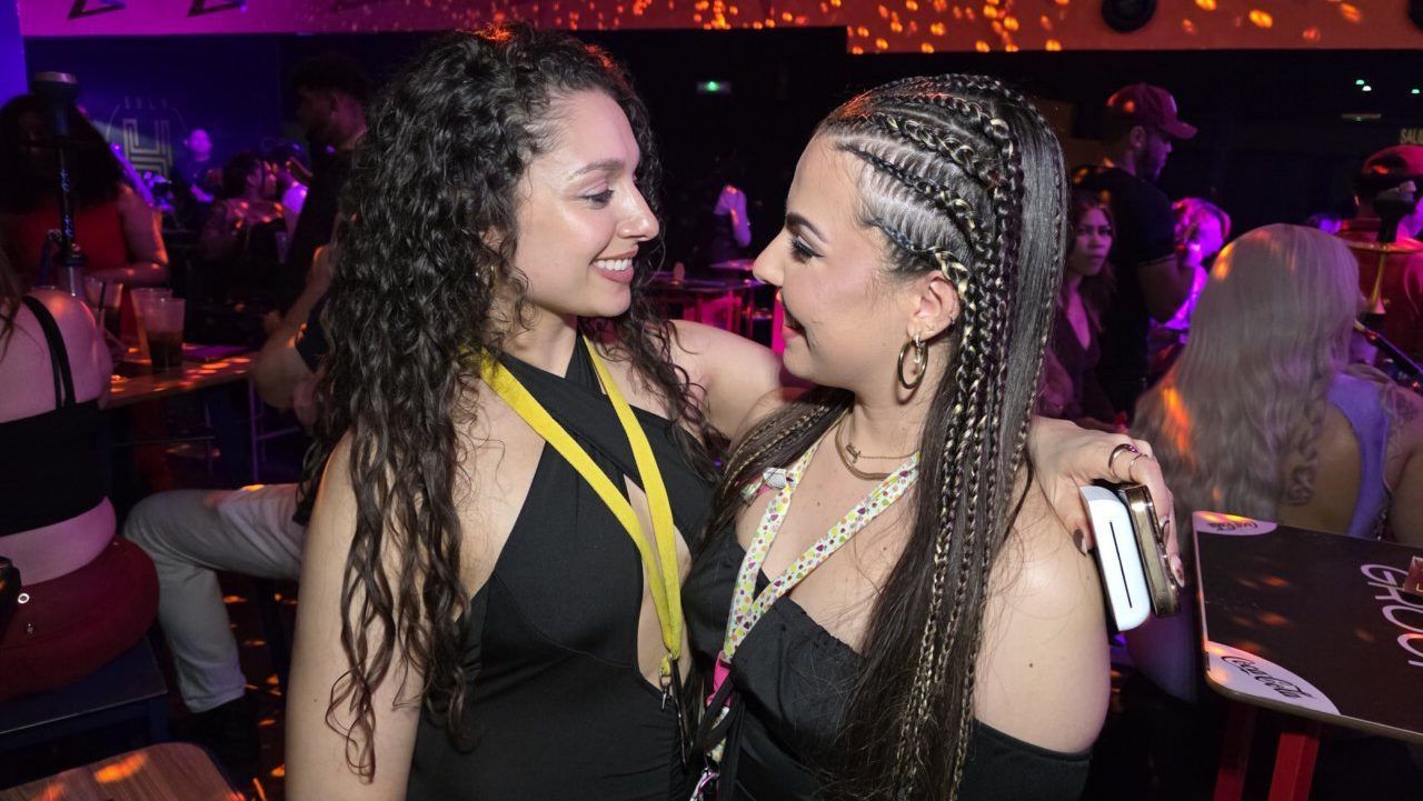 Dos mujeres sonriendo y conversando en un ambiente festivo.