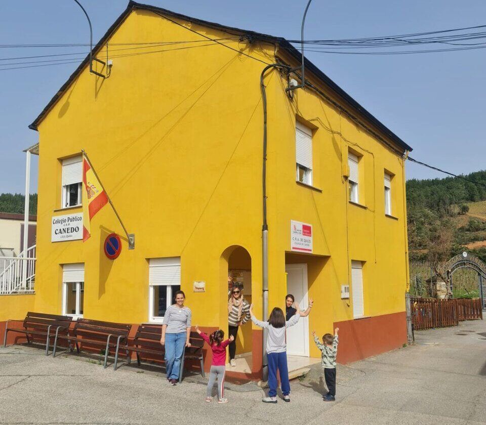 Exterior de la escuela de Canedo con niños y adultos sonriendo