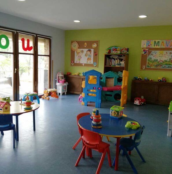 Interior de la escuela infantil en Molinaseca con juguetes y mesas