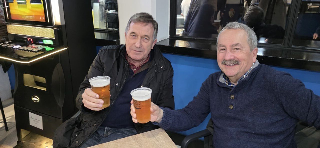 Dos hombres brindando con cervezas en un bar