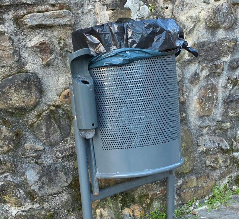 Contenedor de basura en Villafranca del Bierzo junto a una pared de piedra