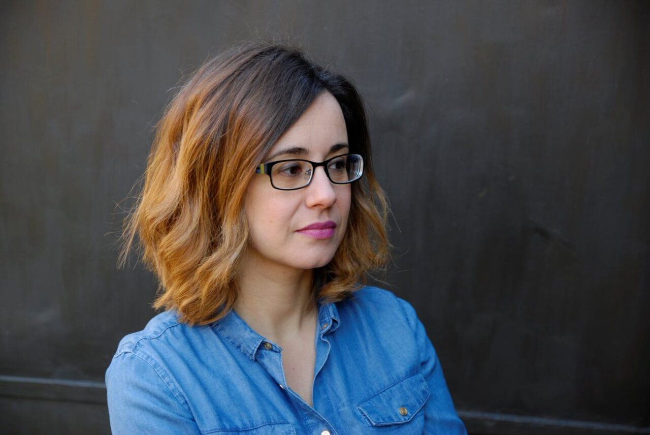 Retrato de Noemí Sabugal con cabello rizado y camisa de mezclilla