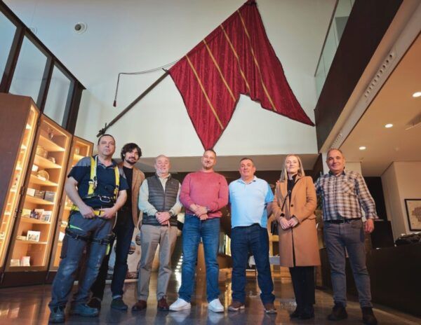 Grupo de personas frente a un gran pendón en el Museo de los Pueblos
