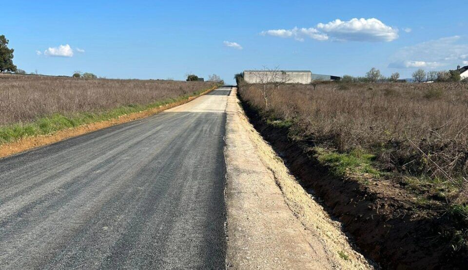 Camino asfaltado en el polígono industrial de Cacabelos bajo un cielo azul