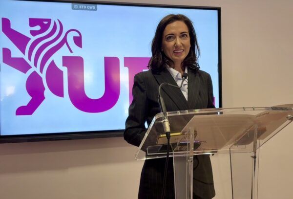 Mujer en conferencia de prensa con logo de UPL de fondo