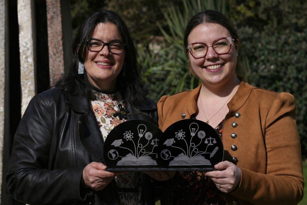 Dos mujeres sonrientes sosteniendo premios de excelencia docente en la Universidad de León