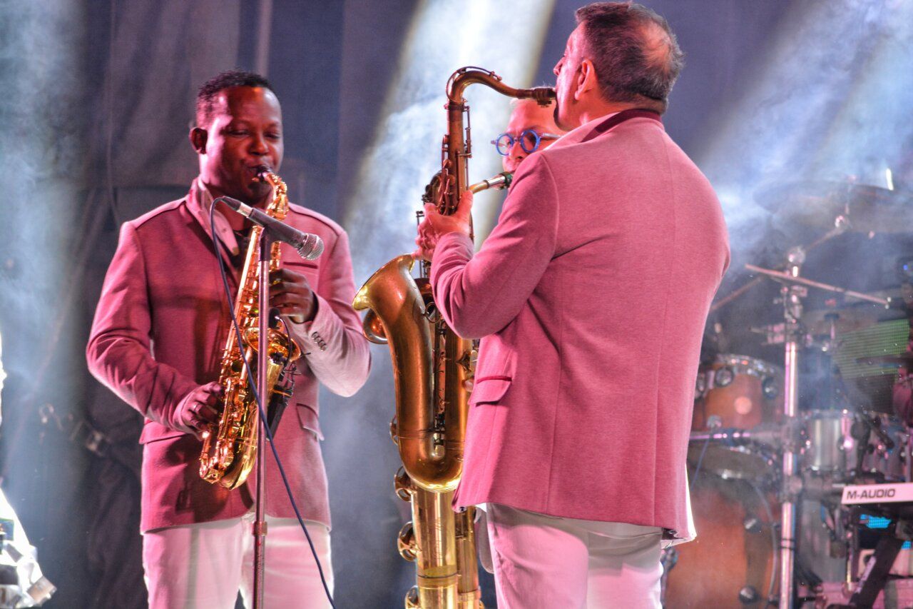 Músicos de la Orquesta Los Satélites tocando instrumentos en un concierto
