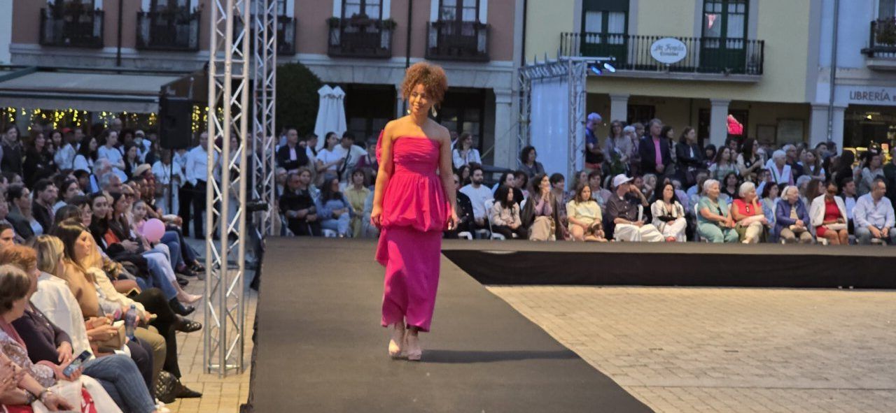Modelo en pasarela con vestido rosa durante desfile de moda