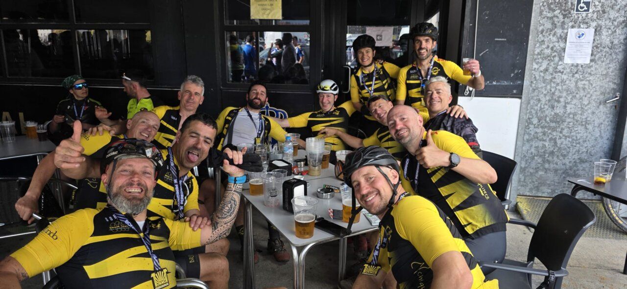 Grupo de ciclistas celebrando con cervezas en un bar