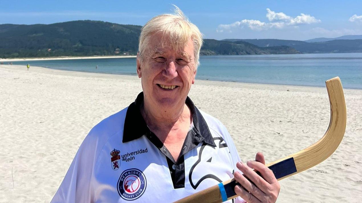 Carlos Figueroa sonriente en la playa con un stick de hockey