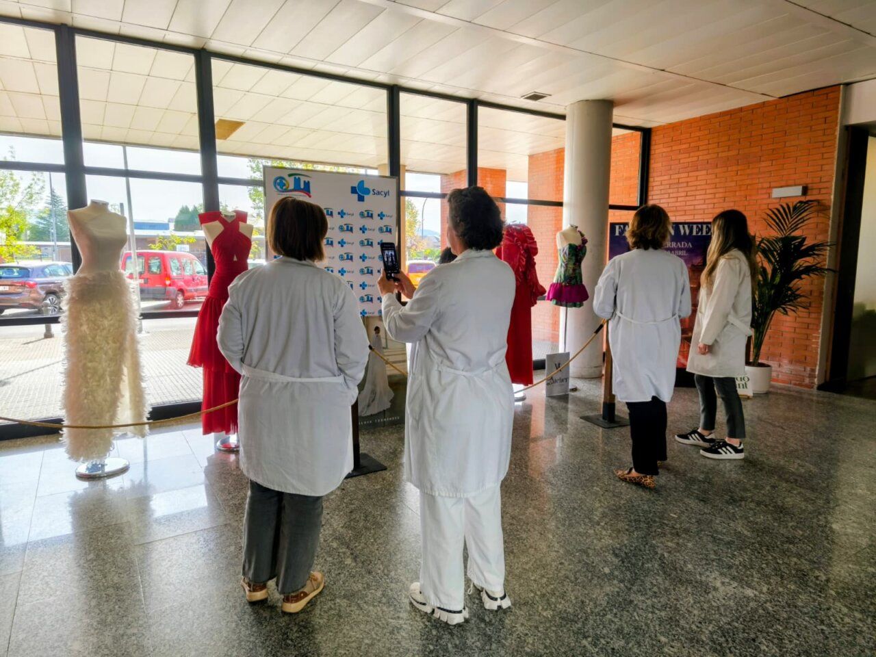 Exposición de moda en el hall del Hospital El Bierzo con maniquíes y visitantes.