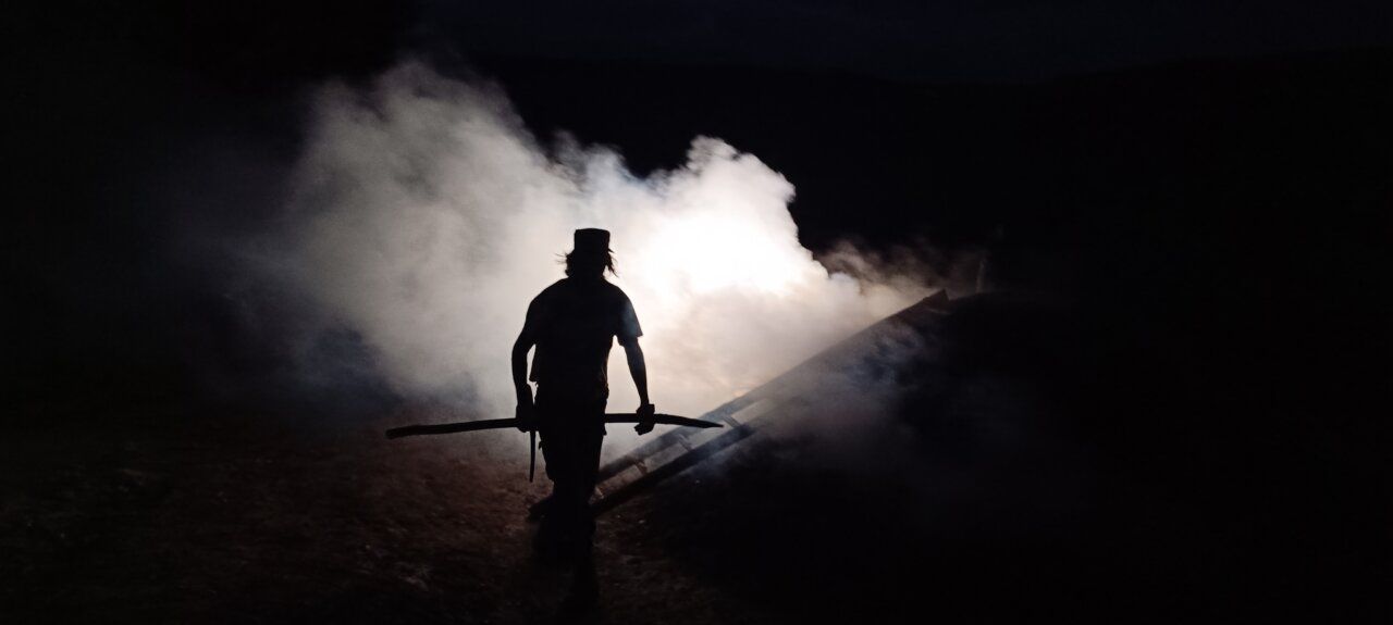 Hombre en la oscuridad extrayendo carbón vegetal en Villar de los Barrios