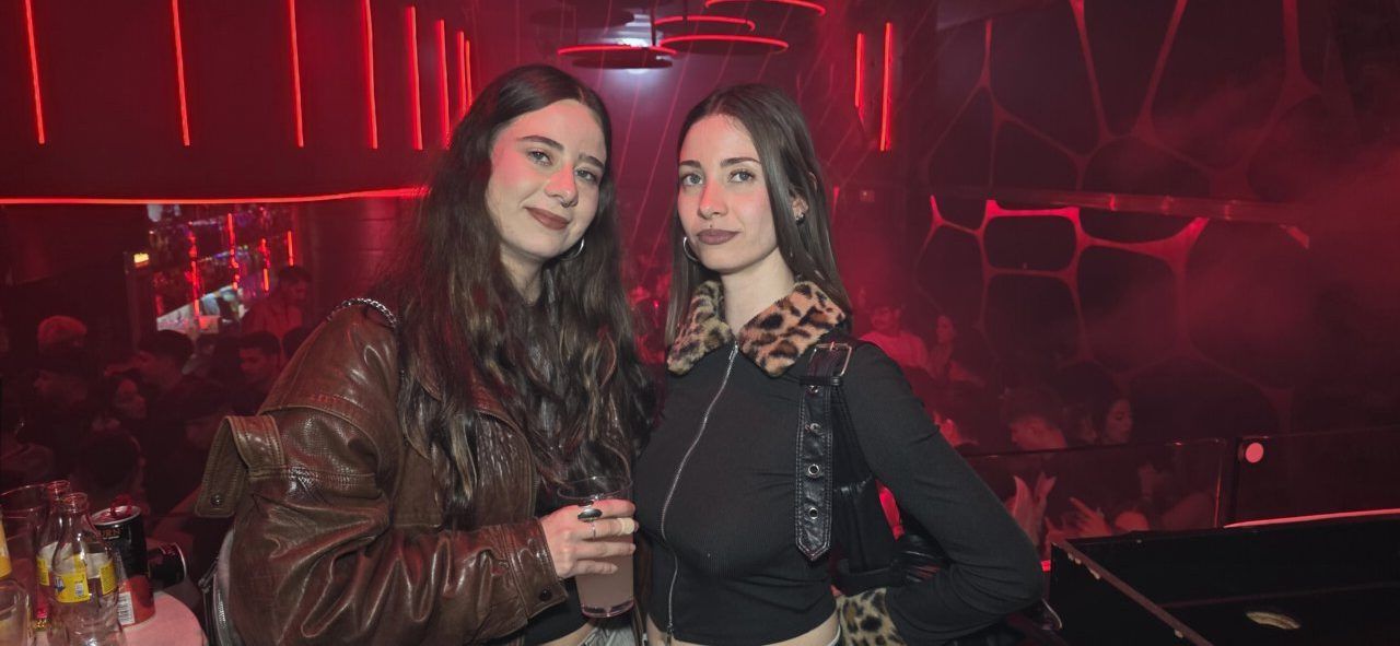 Dos mujeres posando en un bar con luces rojas durante la fiesta