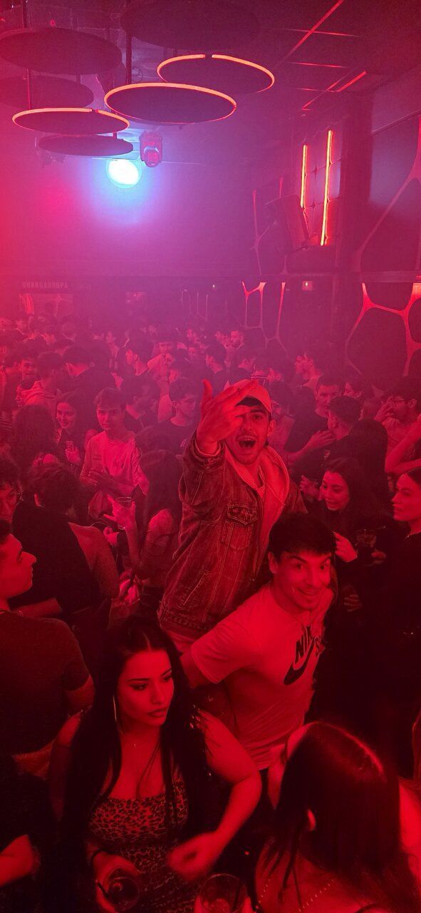 Multitud disfrutando de una fiesta en un club nocturno con luces rojas