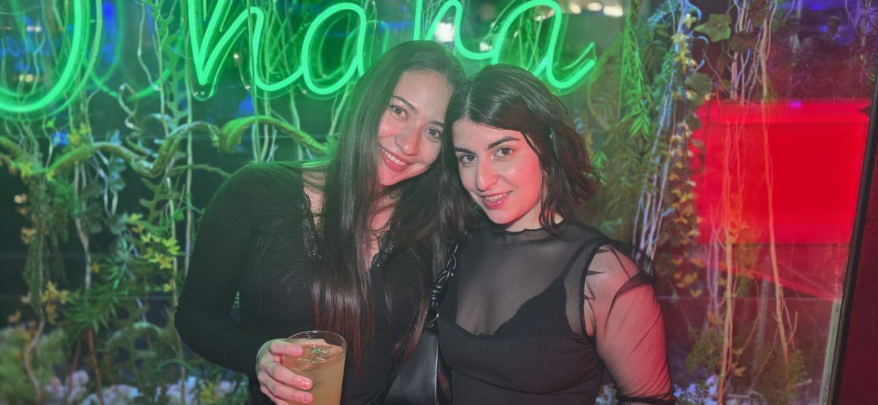 Dos mujeres sonriendo en una fiesta con luces de neón
