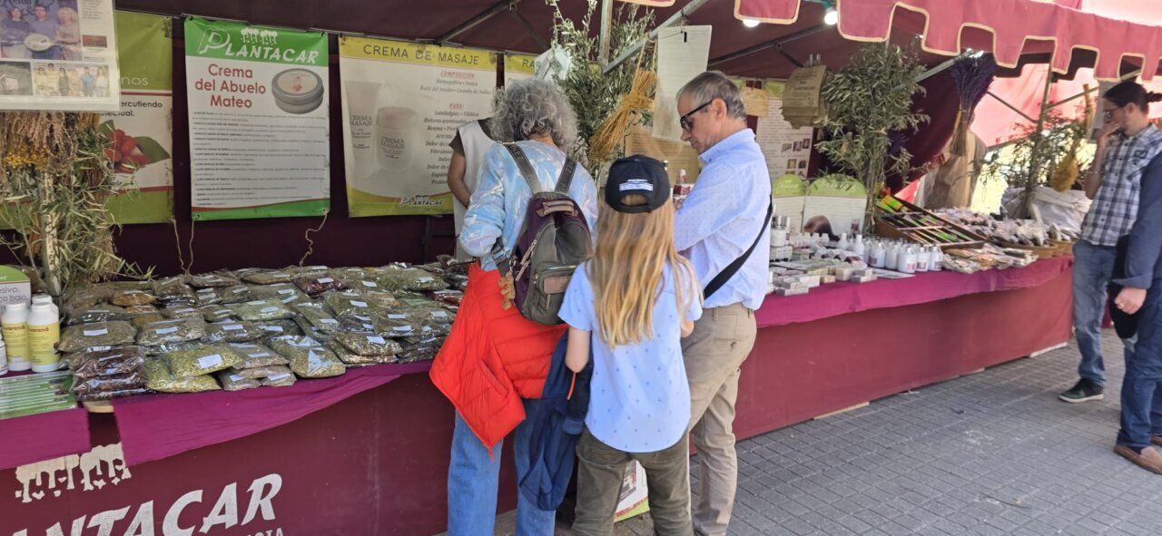 Personas explorando un mercado romano en Ponferrada con productos naturales.