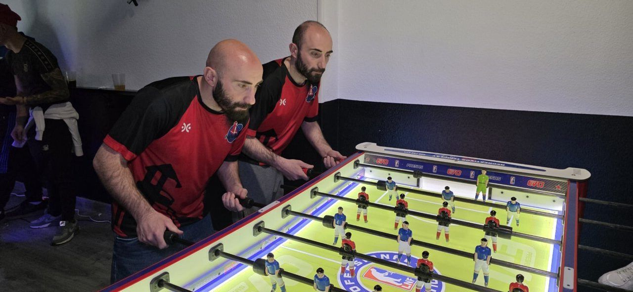 Jugadores compitiendo en un futbolín en el Bar Sueños