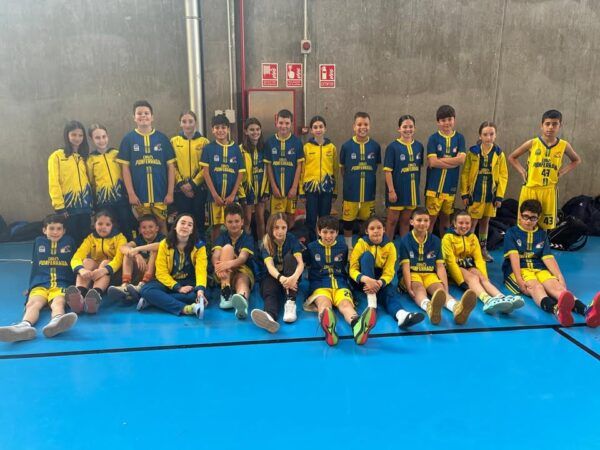 Grupo de niños y niñas en uniforme de baloncesto en un gimnasio