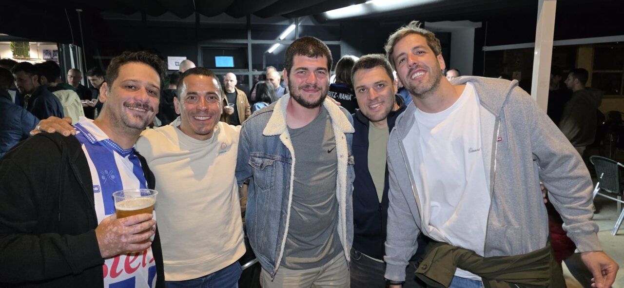 Grupo de amigos posando en un bar con cervezas