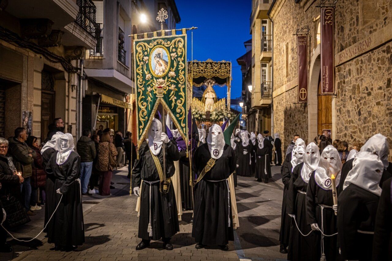 Participantes en la Procesión del Silencio en La Bañeza con capirotes y estandarte.