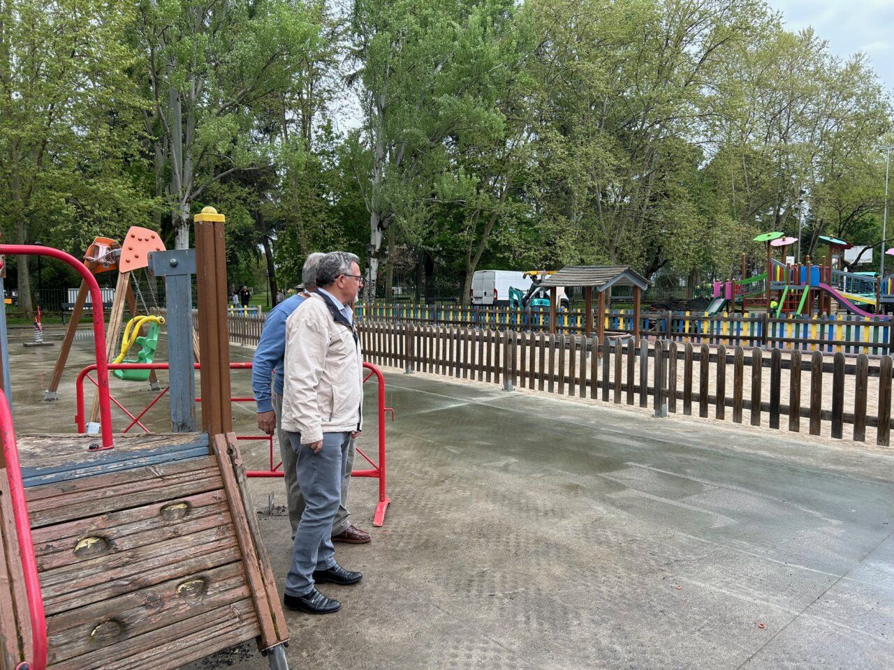 Hombres observando juegos infantiles en un parque renovado