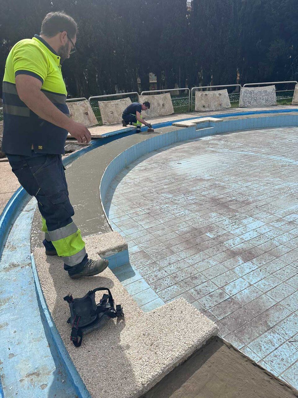 Trabajadores reparando el vaso de chapoteo en las piscinas del Plantío