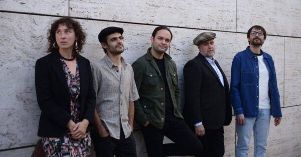 Grupo de músicos posando frente a una pared de piedra