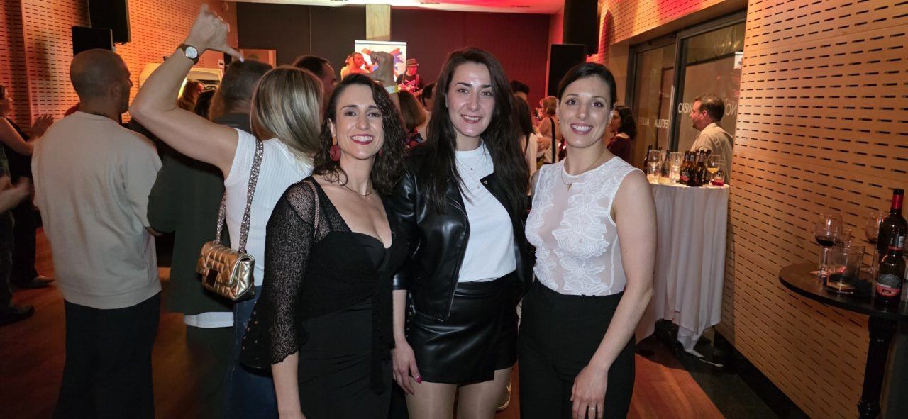 Tres mujeres posando en una fiesta del casino con fondo de gente bailando