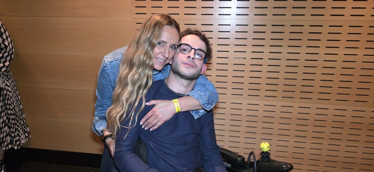 Pareja sonriente en evento con fondo de madera