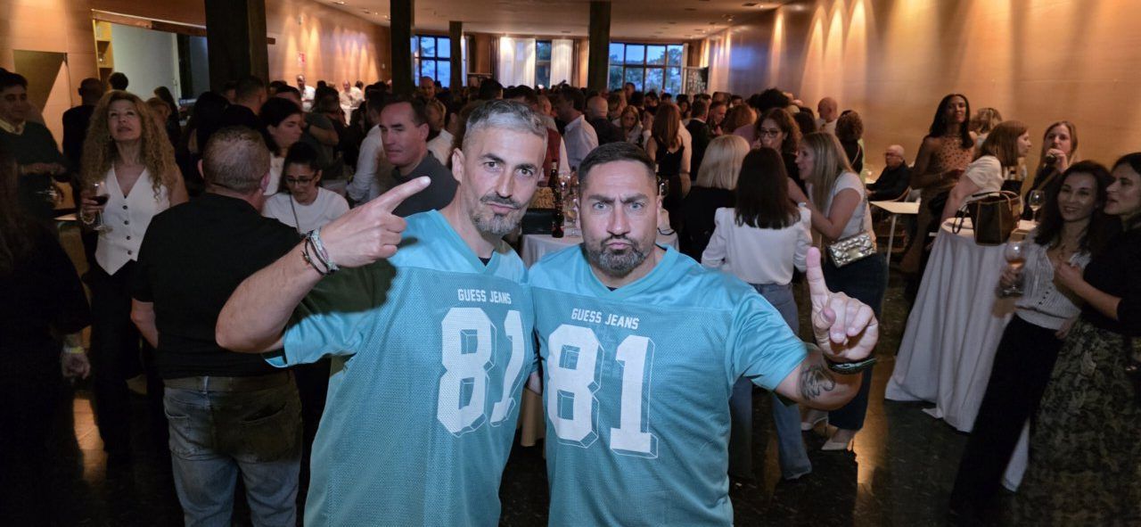 Dos hombres posando en una fiesta con gente de fondo