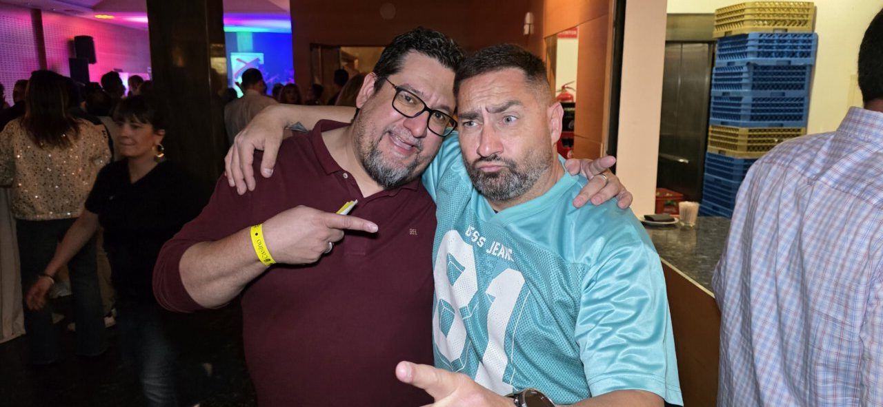 Dos hombres posando divertidos en una fiesta de aniversario.
