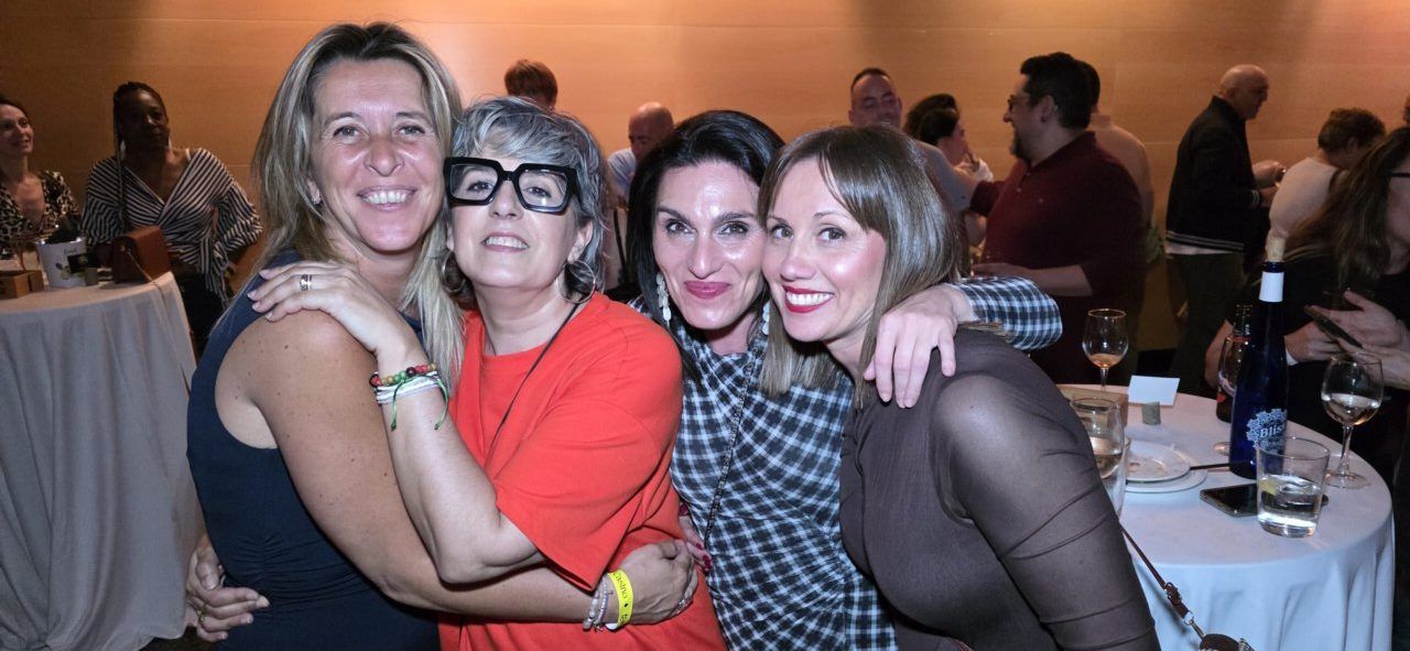 Cuatro mujeres sonriendo y abrazándose en una celebración