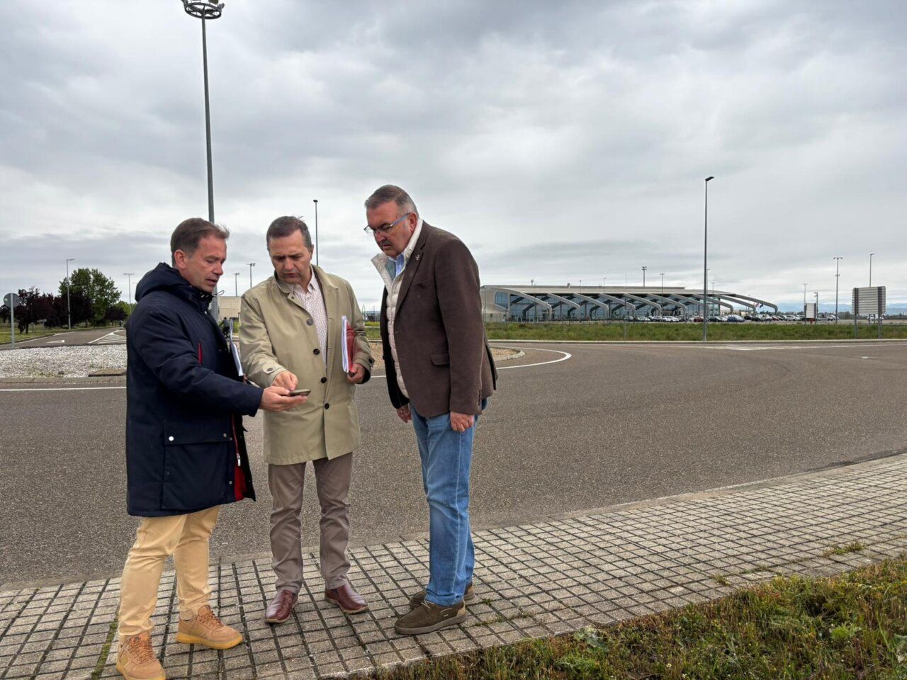 Tres hombres revisando planos en el acceso al Aeropuerto de León