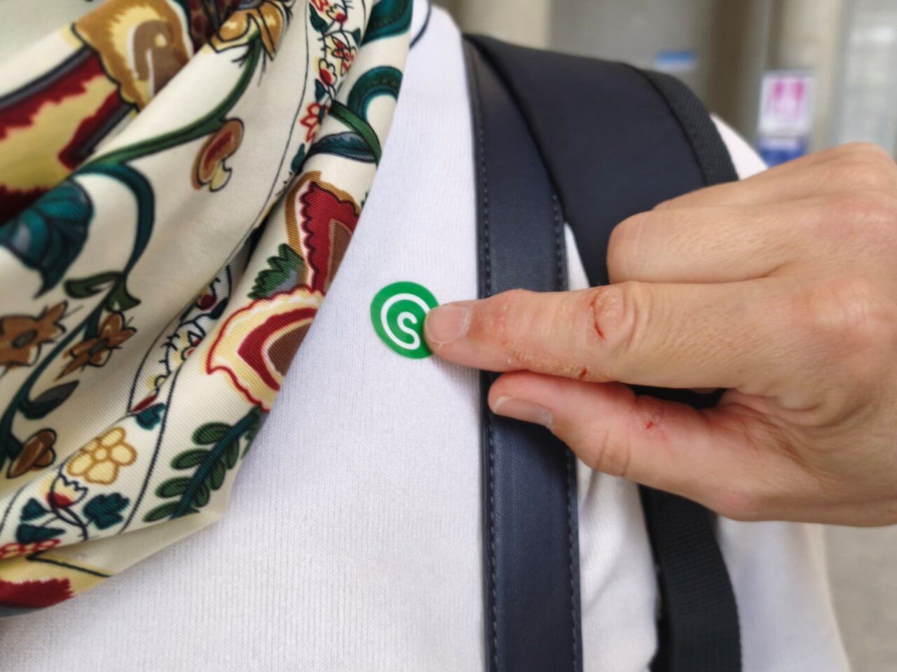 Persona colocando una pegatina verde en su ropa durante evento solidario